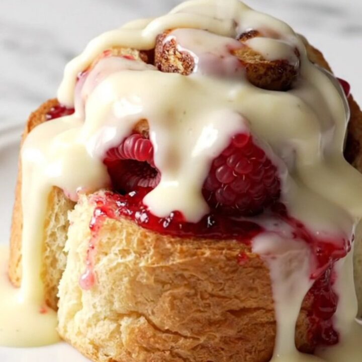 A close-up of a raspberry white chocolate cinnamon roll bake in a pink slow cooker.