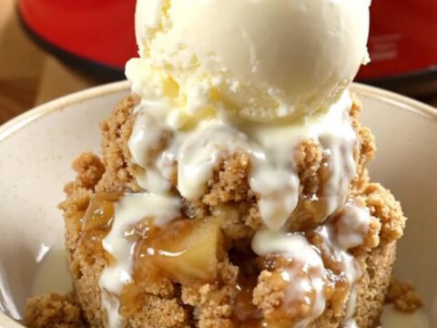 A steaming crockpot filled with tender Honeycrisp apple wedges under a golden, buttery oat crumble.