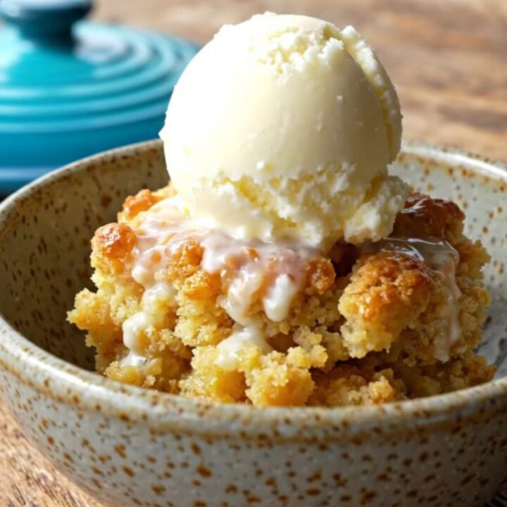 A close-up view of the golden pineapple mango crisp in a turquoise slow cooker with a crunchy coconut topping.