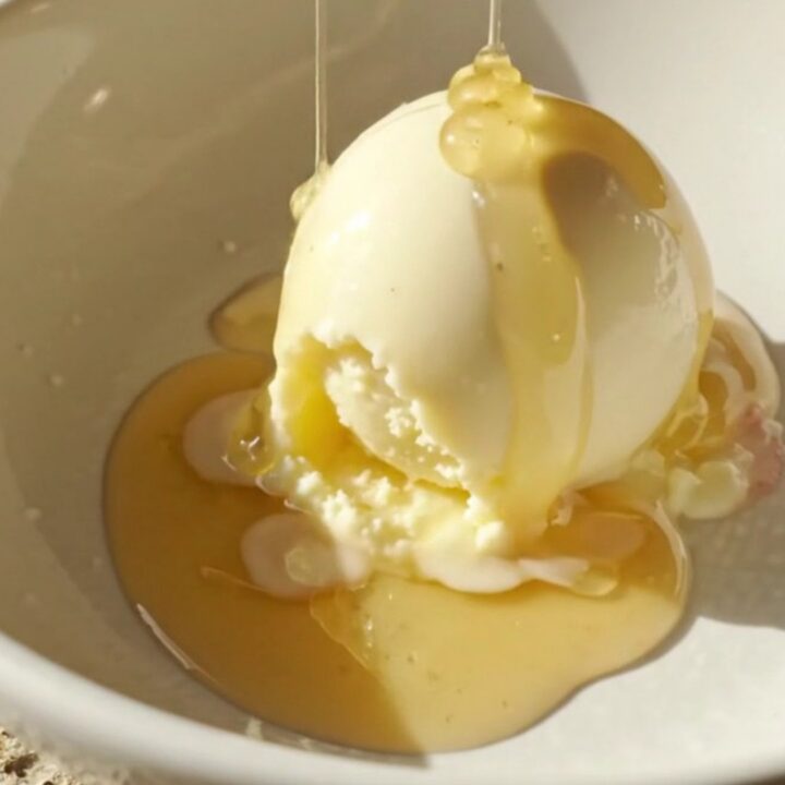 A close-up of a blackberry honey cobbler in a lavender ceramic slow cooker with golden biscuits on top.