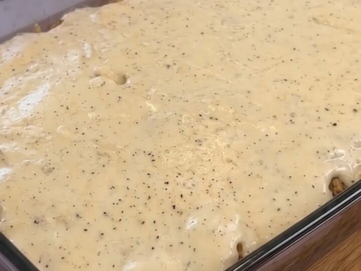 A glass baking dish filled with loaded tater tot breakfast casserole topped with warm country pepper gravy