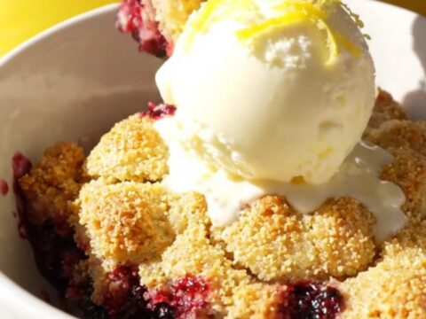A warm, golden cornmeal cobbler in a yellow ceramic slow cooker with bubbling blackberry filling.
