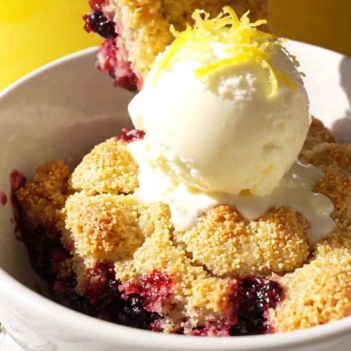 A warm, golden cornmeal cobbler in a yellow ceramic slow cooker with bubbling blackberry filling.