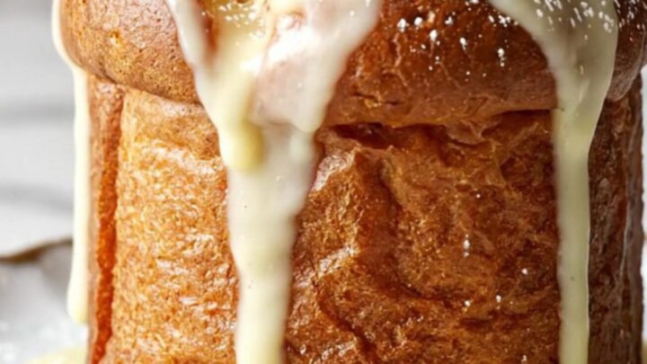 A close-up of a golden, creamy white chocolate and cranberry bread pudding served in a festive holiday setting.
