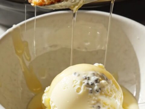 A close-up view of the golden, almond-crusted peach croissant bread pudding in a ceramic Crockpot.