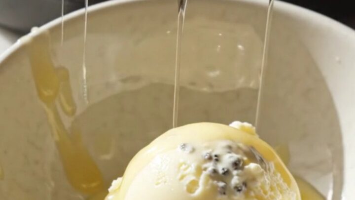 A close-up view of the golden, almond-crusted peach croissant bread pudding in a ceramic Crockpot.