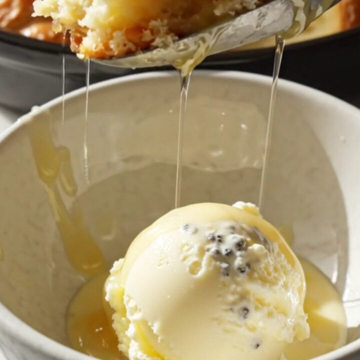A close-up view of the golden, almond-crusted peach croissant bread pudding in a ceramic Crockpot.