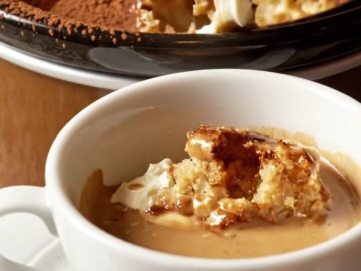 A warm, creamy tiramisu brioche bread pudding in a mocha-brown ceramic crockpot, dusted with cocoa powder.