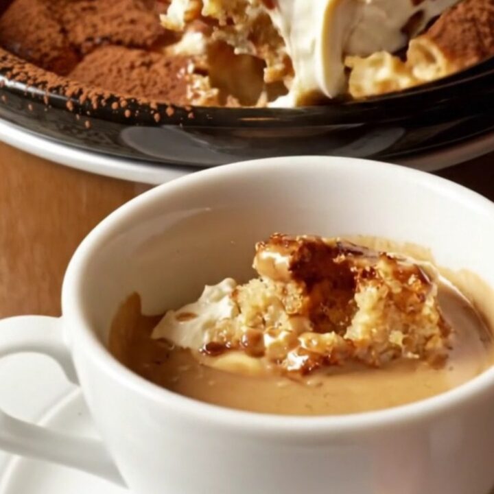 A warm, creamy tiramisu brioche bread pudding in a mocha-brown ceramic crockpot, dusted with cocoa powder.