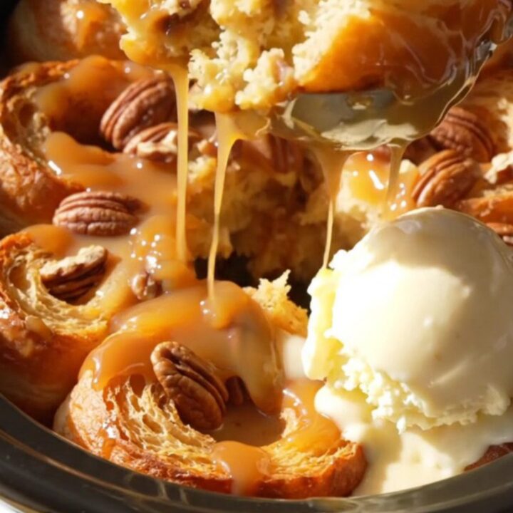 A golden-brown maple pecan bread pudding in a yellow crockpot, topped with a glossy maple glaze.