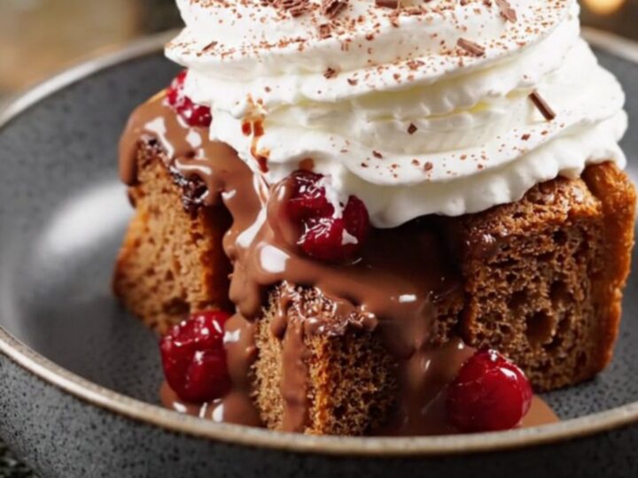 A steaming bowl of Black Forest bread pudding topped with whipped cream and chocolate shavings.