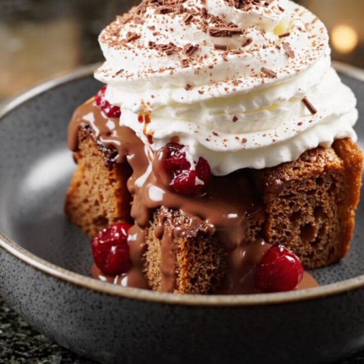 A steaming bowl of Black Forest bread pudding topped with whipped cream and chocolate shavings.