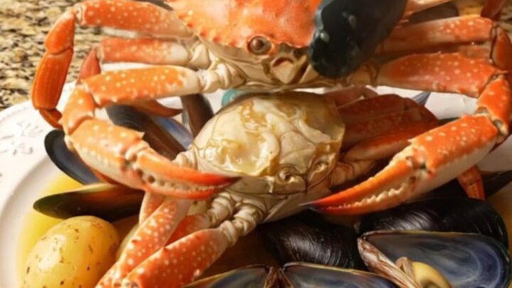 A steaming platter featuring Dungeness crab clusters, open mussels
