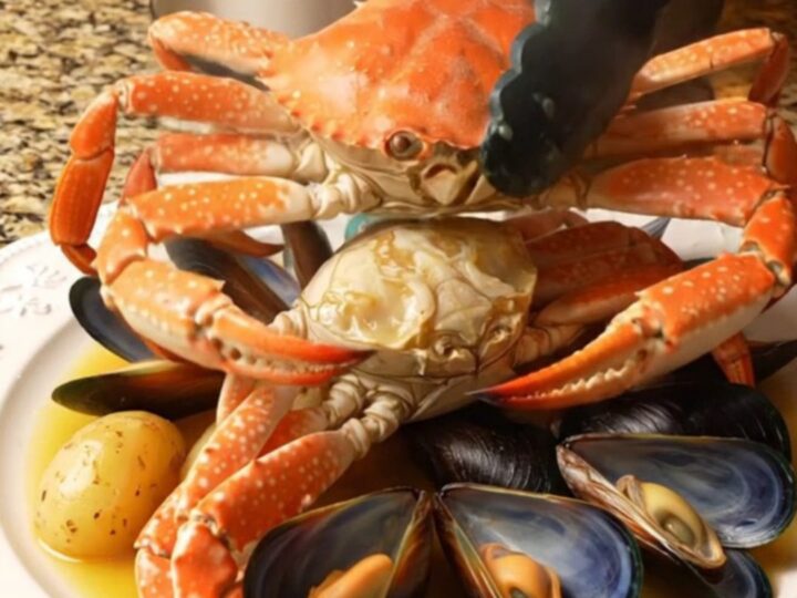 A steaming platter featuring Dungeness crab clusters, open mussels
