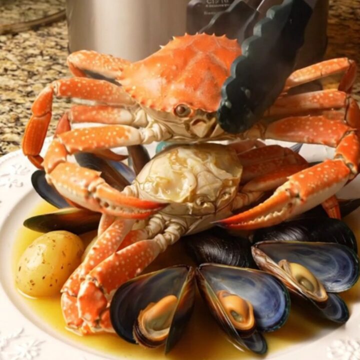 A steaming platter featuring Dungeness crab clusters, open mussels