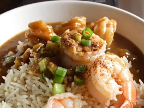 A steaming bowl of dark, rich Louisiana seafood and okra gumbo served over a mound of fluffy white rice.