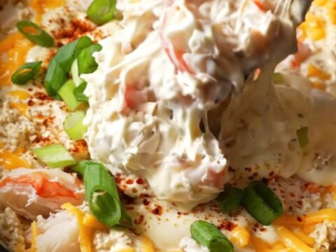 A burgundy ceramic Crockpot filled with creamy, bubbling Maryland lump crab imperial dip topped with Old Bay.