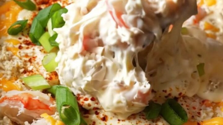 A burgundy ceramic Crockpot filled with creamy, bubbling Maryland lump crab imperial dip topped with Old Bay.