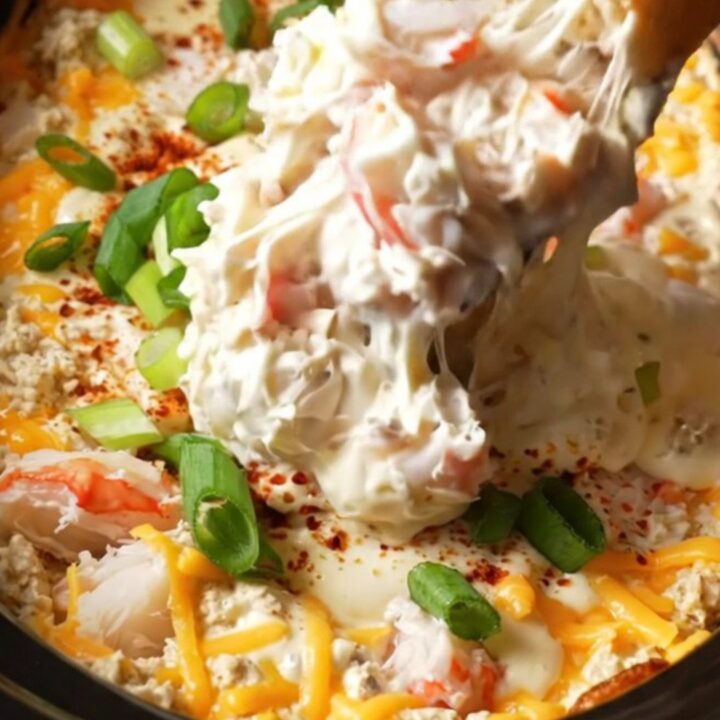A burgundy ceramic Crockpot filled with creamy, bubbling Maryland lump crab imperial dip topped with Old Bay.