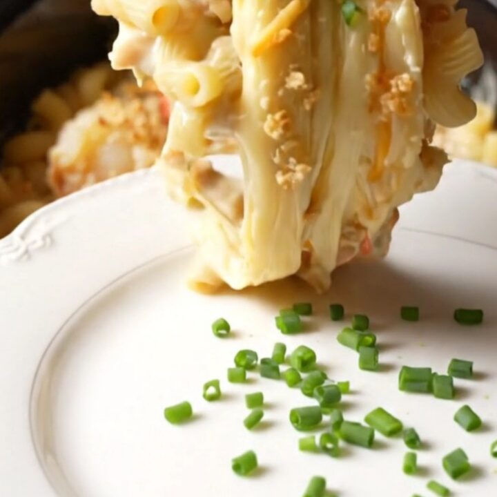 A close-up of a champagne-gold ceramic slow cooker filled with creamy lobster mac and cheese topped with golden brioche