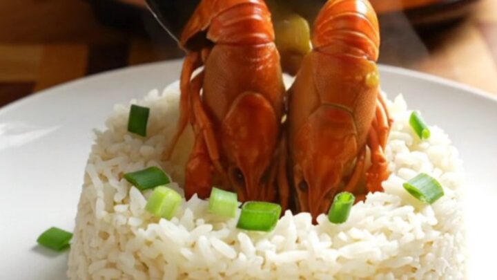 A steaming bowl of rich, golden crawfish etouffee served over a bed of fluffy white jasmine rice.
