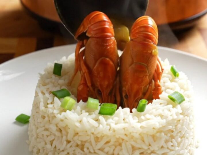 A steaming bowl of rich, golden crawfish etouffee served over a bed of fluffy white jasmine rice.