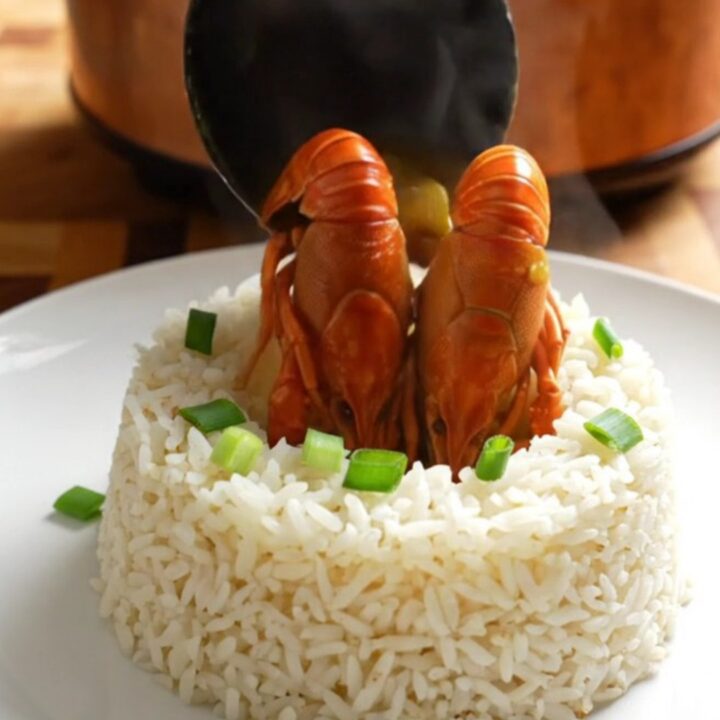 A steaming bowl of rich, golden crawfish etouffee served over a bed of fluffy white jasmine rice.