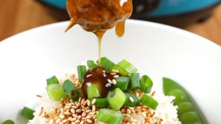 A close-up view of sticky teriyaki chicken meatballs glistening with glaze in a ceramic slow cooker.