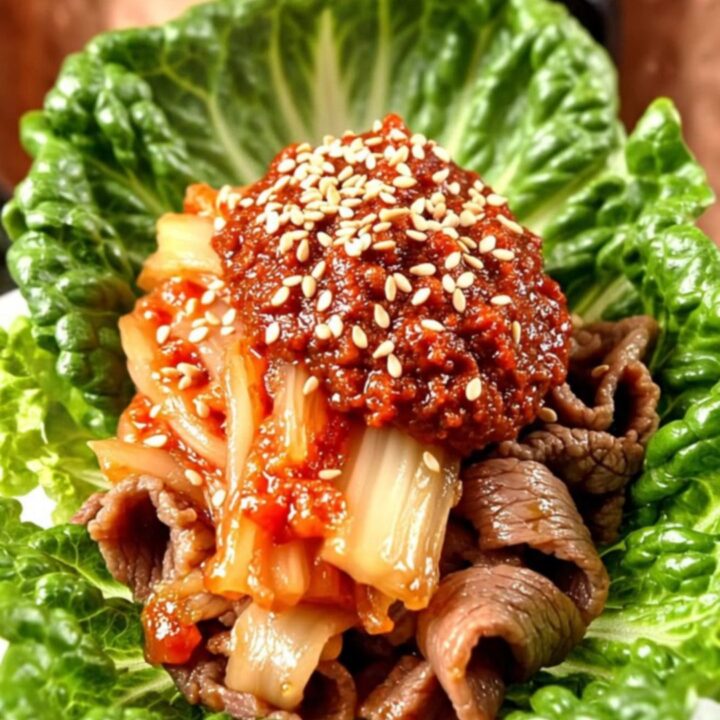 A copper-toned ceramic crockpot filled with caramelized Korean Bulgogi beef ribbons and sliced onions.