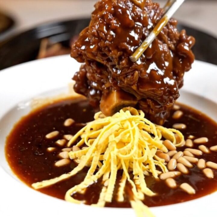 A cinematic close-up of tender Korean Galbi-Jjim braised short ribs in a glossy soy-pear glaze inside a ceramic slow cooker.