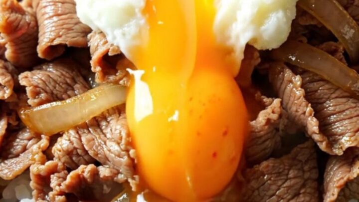 A steaming bowl of Japanese Gyudon with tender beef and onions over rice, topped with a runny onsen egg.