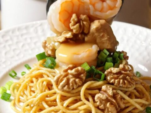 A close-up of honey walnut chicken and shrimp in a slow cooker with a creamy glaze and walnuts.