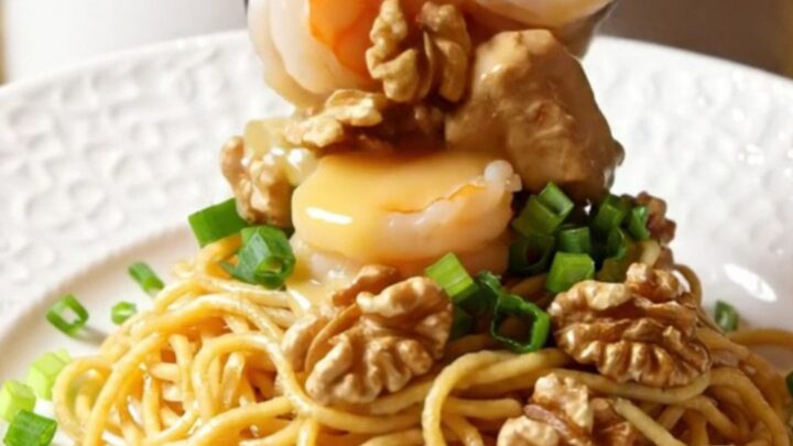 A close-up of honey walnut chicken and shrimp in a slow cooker with a creamy glaze and walnuts.