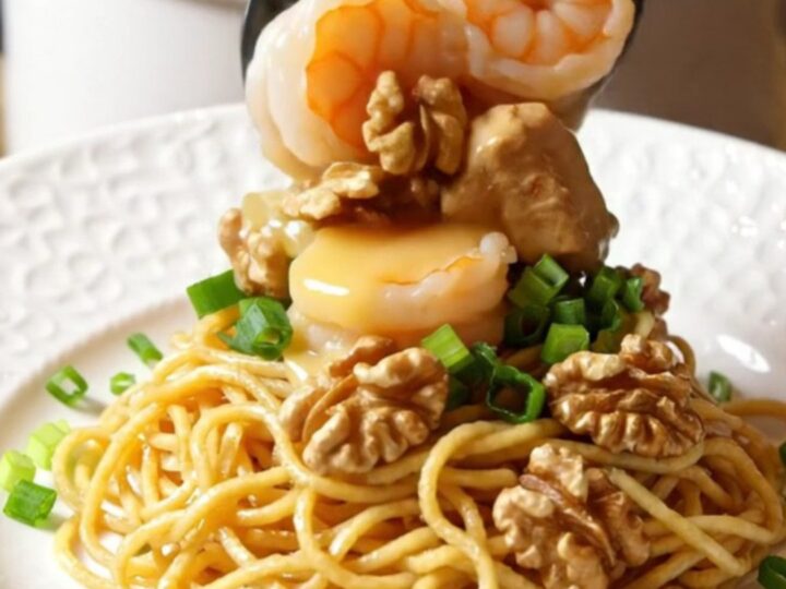 A close-up of honey walnut chicken and shrimp in a slow cooker with a creamy glaze and walnuts.