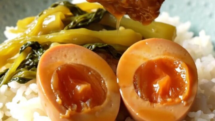 A ceramic slow cooker filled with braised pork belly cubes and dark mahogany eggs in a rich coconut caramel sauce.