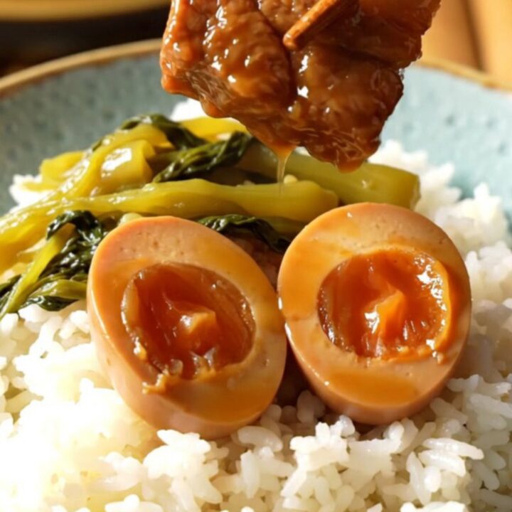 A ceramic slow cooker filled with braised pork belly cubes and dark mahogany eggs in a rich coconut caramel sauce.