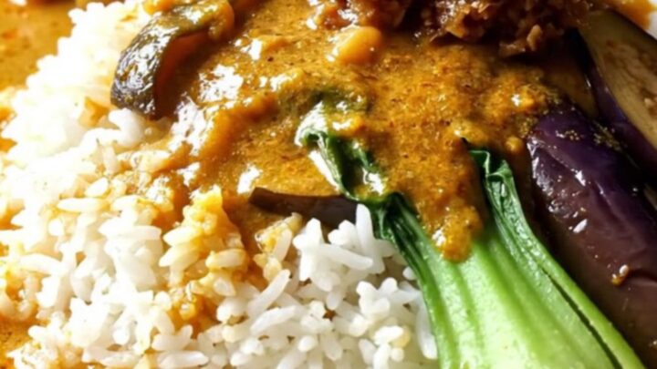 Close-up of golden-orange Filipino Kare-Kare with oxtails and vegetables in a ceramic Crockpot.