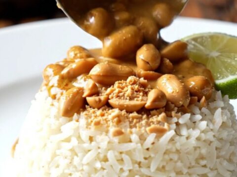 A close-up of a bowl filled with creamy Thai red coconut peanut chicken curry over jasmine rice.