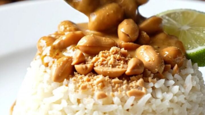 A close-up of a bowl filled with creamy Thai red coconut peanut chicken curry over jasmine rice.