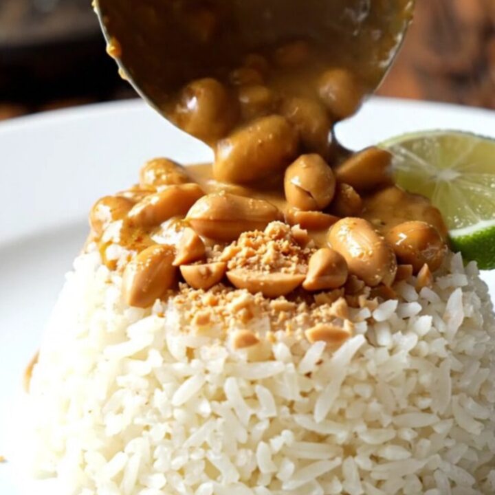 A close-up of a bowl filled with creamy Thai red coconut peanut chicken curry over jasmine rice.