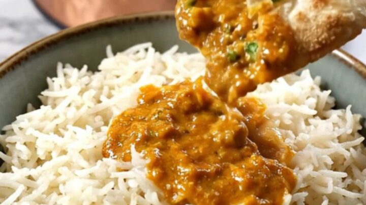 A copper-finished Crockpot revealing steaming orange-red Chicken Tikka Masala with a velvety, creamy texture.
