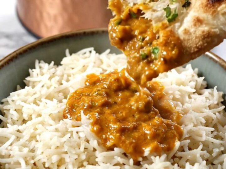 A copper-finished Crockpot revealing steaming orange-red Chicken Tikka Masala with a velvety, creamy texture.