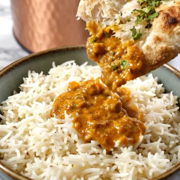 A copper-finished Crockpot revealing steaming orange-red Chicken Tikka Masala with a velvety, creamy texture.