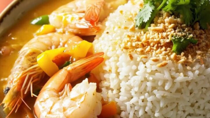 A vibrant Brazilian Moqueca stew served in a coral ceramic Crockpot, showing chunks of white fish and jumbo shrimp.