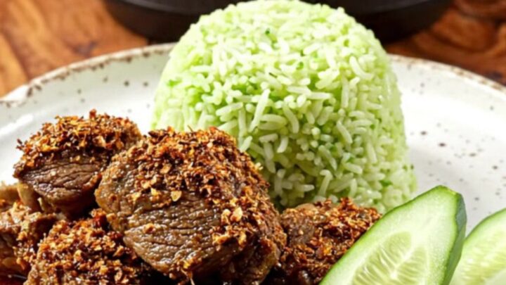 A close-up of dark, caramelized Indonesian Beef Rendang served in a ceramic bowl with steamed pandan rice.