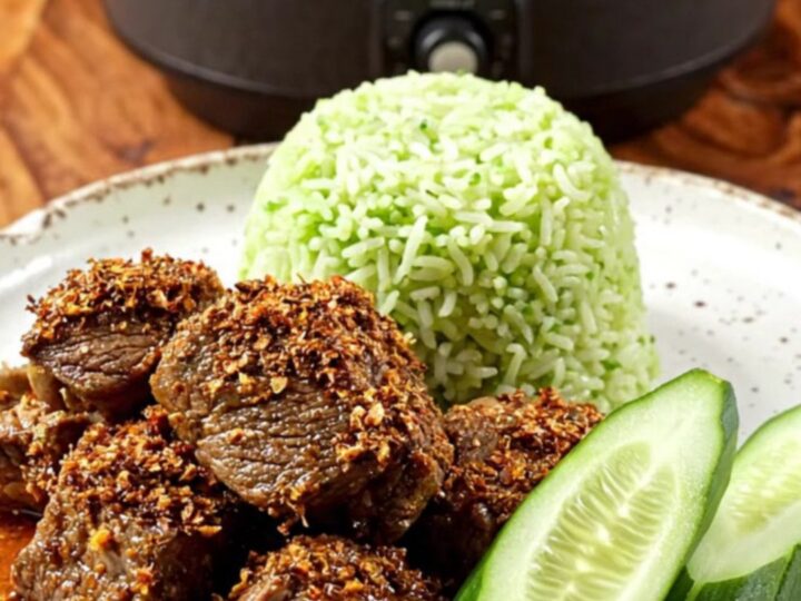A close-up of dark, caramelized Indonesian Beef Rendang served in a ceramic bowl with steamed pandan rice.