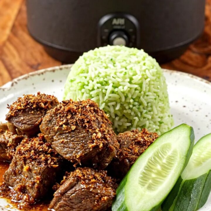 A close-up of dark, caramelized Indonesian Beef Rendang served in a ceramic bowl with steamed pandan rice.