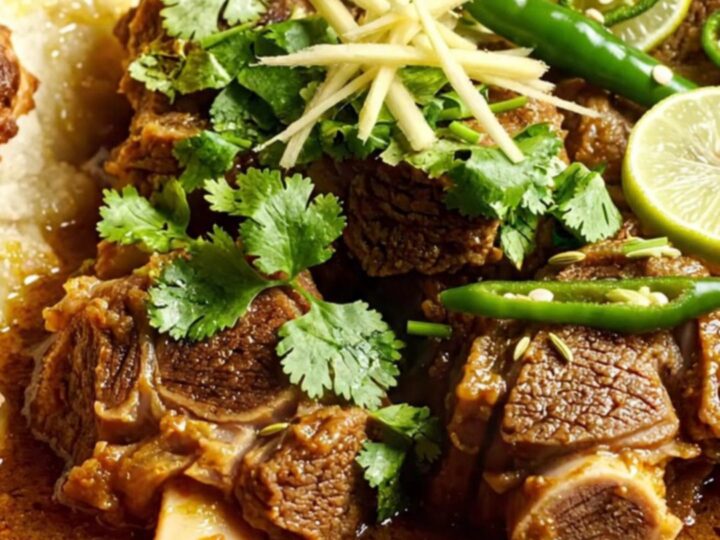A close-up of a bronze ceramic bowl filled with steaming Pakistani Beef Nihari, topped with fresh ginger and cilantro.