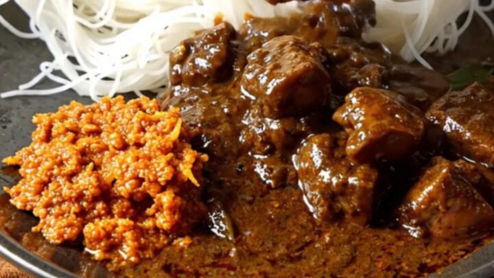 A close-up of a dark, aromatic Sri Lankan black pork curry served in a ceramic bowl with tender meat.
