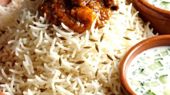 A close-up view of fiery Goan Pork Vindaloo in a ruby ceramic crockpot with a rich red sauce.